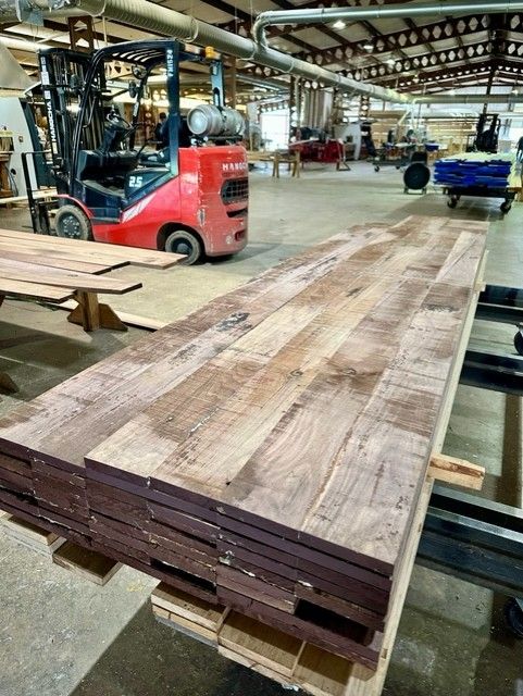 A forklift is moving a stack of wood in a factory.