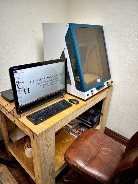 A computer is sitting on a wooden desk next to a chair.