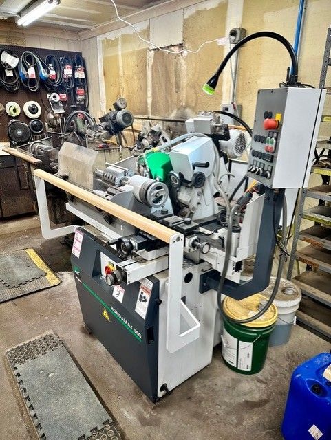A machine is sitting in a garage next to a bucket of oil.
