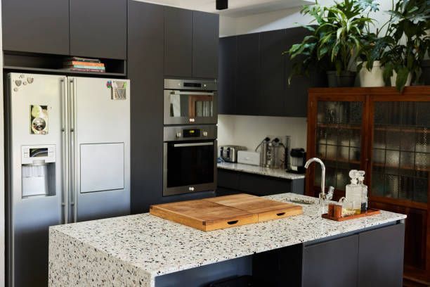 A kitchen with a cutting board on the counter and a refrigerator.