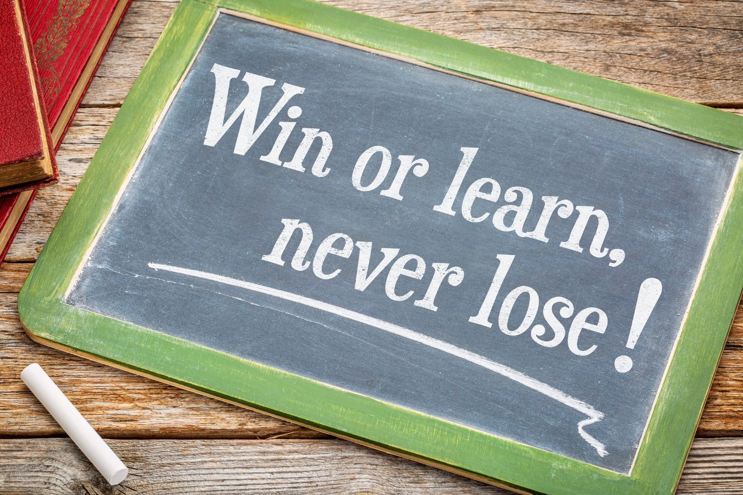 A chalkboard with the words win or learn never lose written on it.