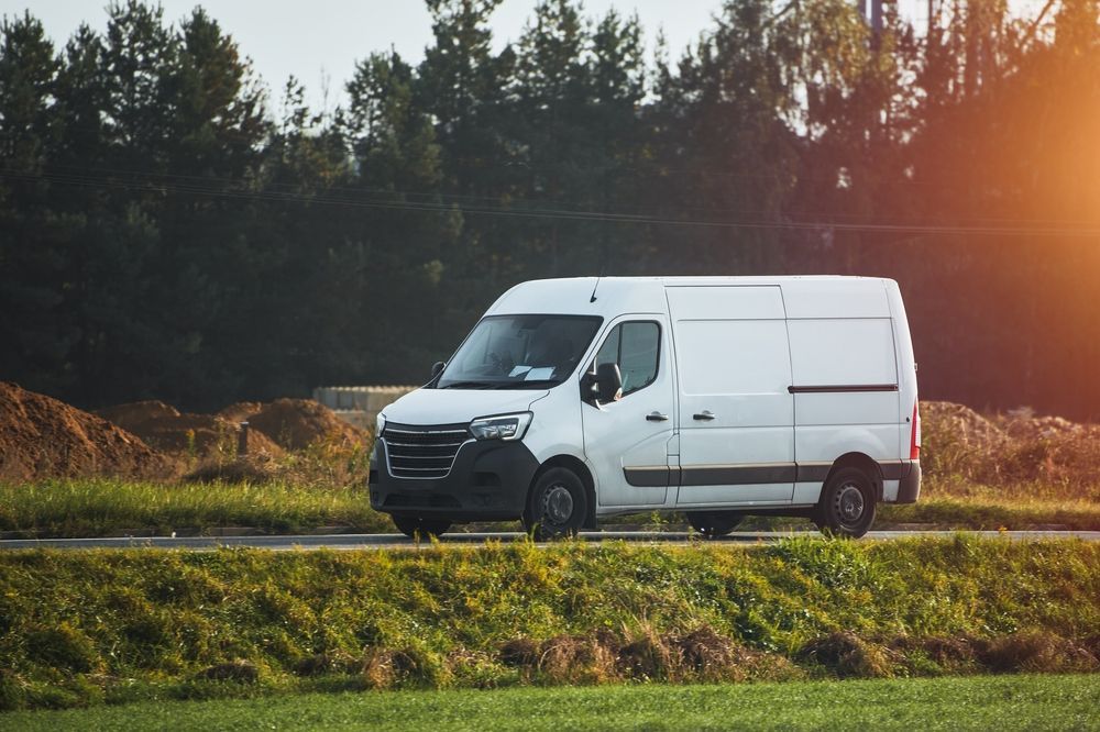 White Cargo Van Driving on a Road Next to a Grassy Field — Mid Coast Smash Repairs In Forster, NSW