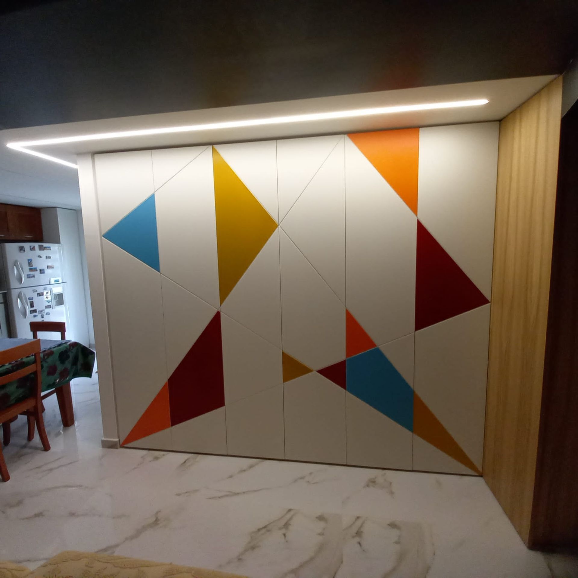 Armadio bianco con forme geometriche colorate e illuminazione dall'alto.