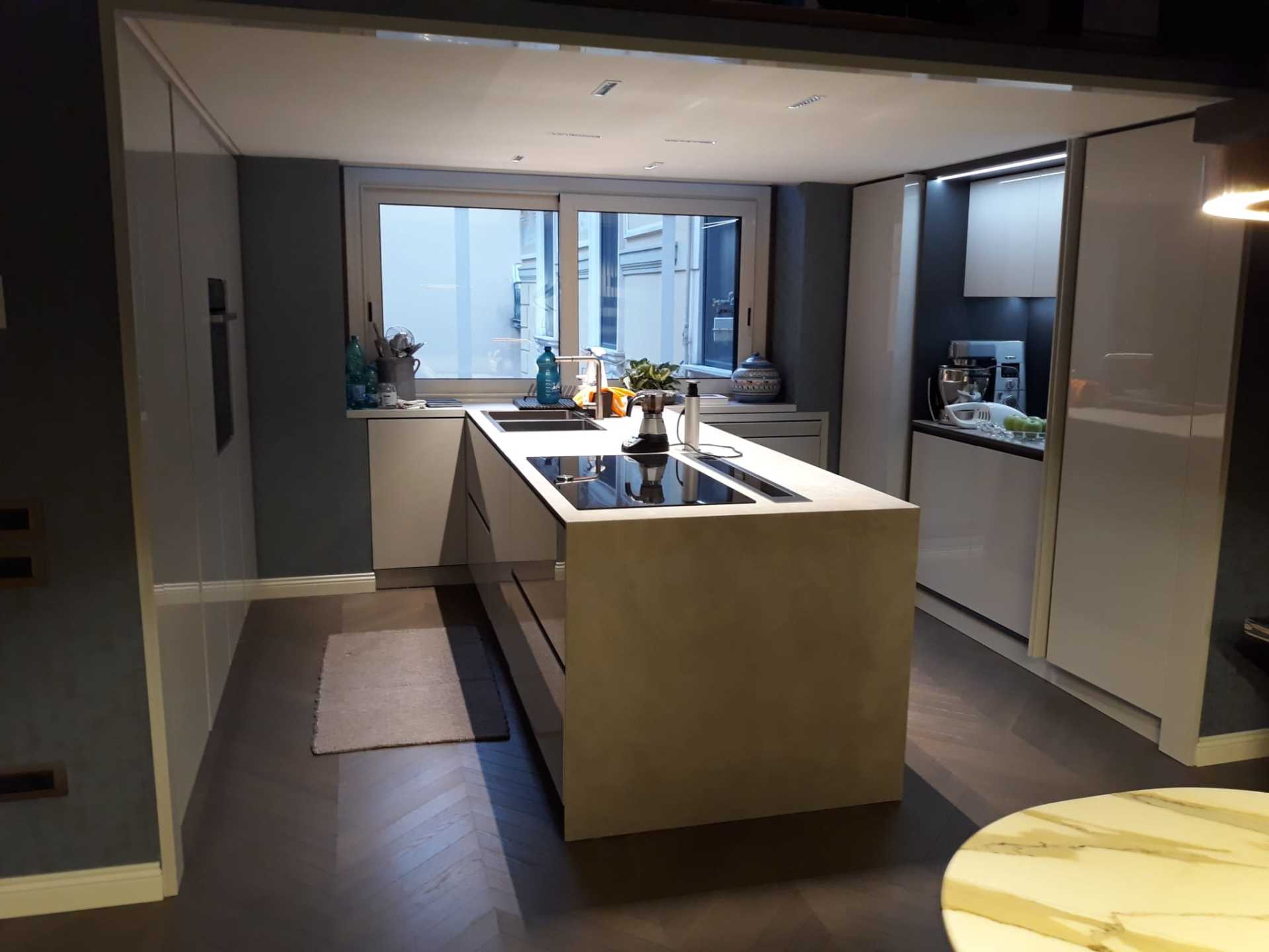 Cucina moderna con isola, mobili grigio scuro, elettrodomestici bianchi e finestra.