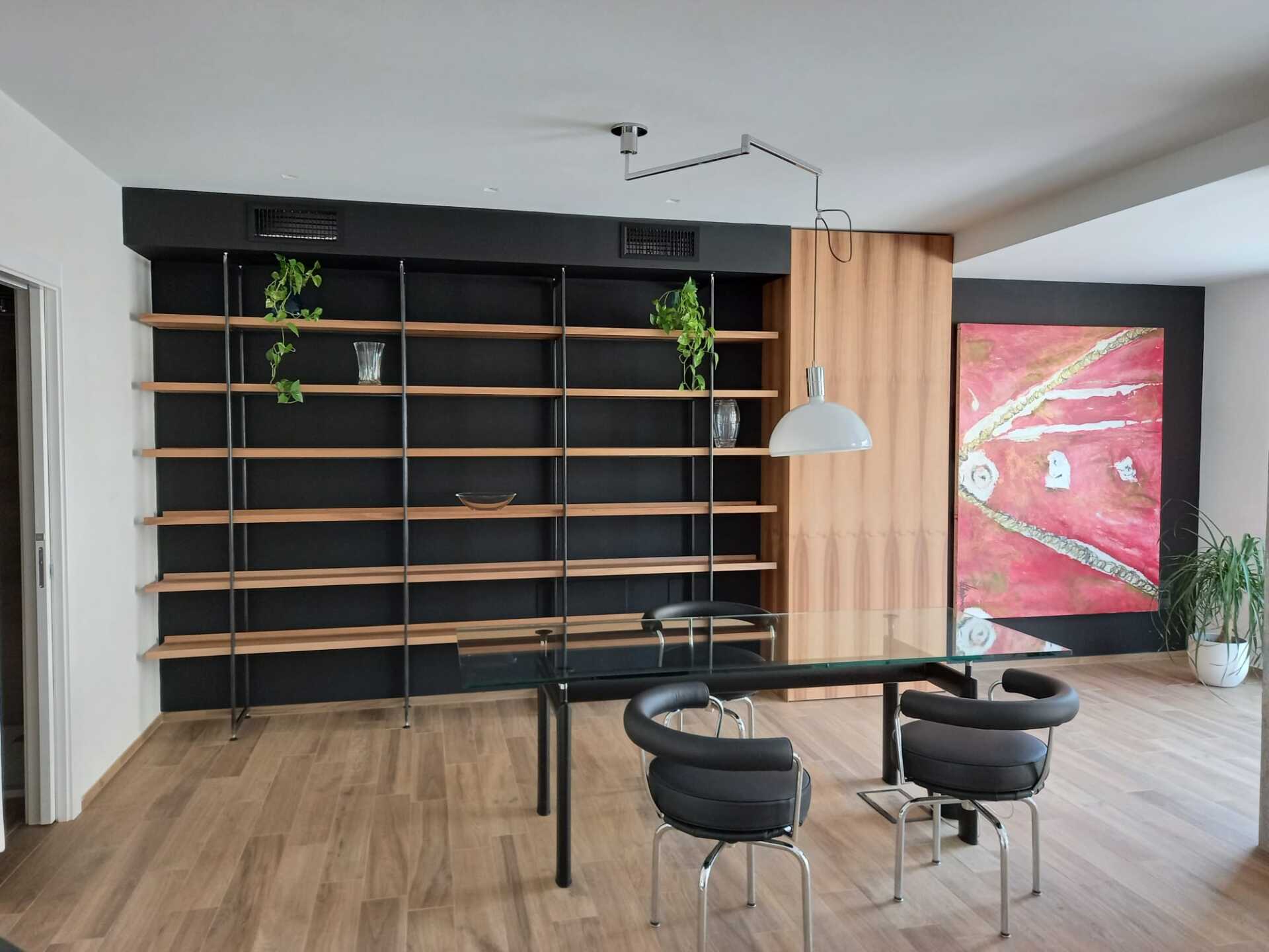 Stanza moderna con scaffali neri, tavolo, sedie e grandi opere d'arte astratte.