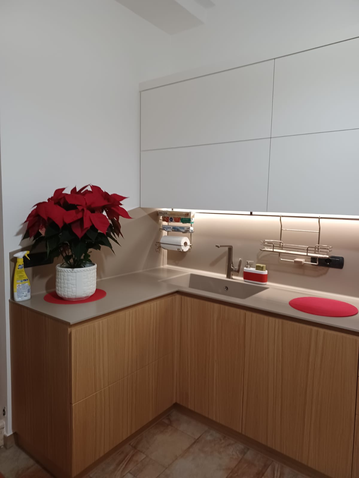 Angolo cottura moderno con mobili in legno, pensili bianchi e una stella di Natale rossa.