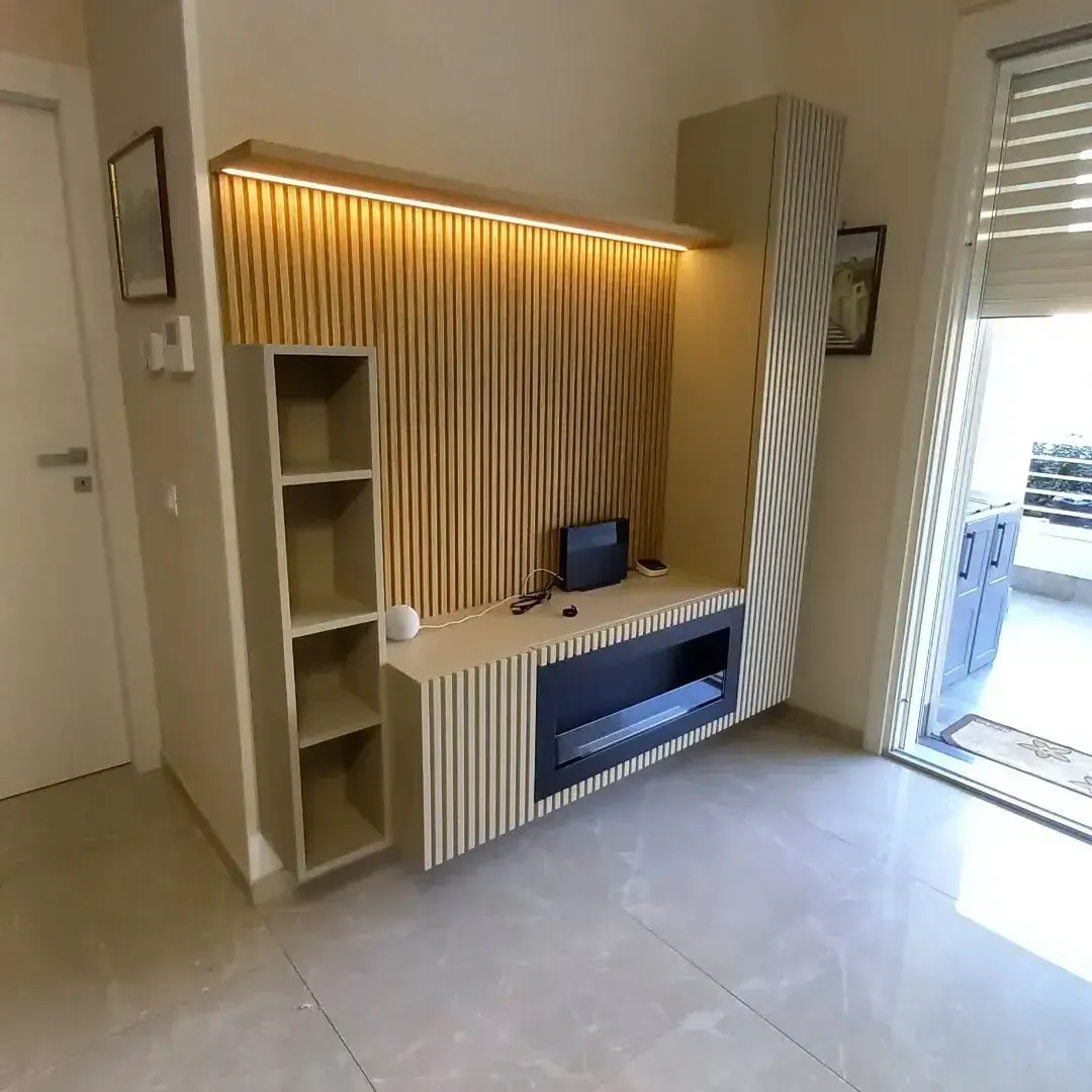 Moderno centro di intrattenimento integrato con fondale in legno, mensole e mobile TV in soggiorno.