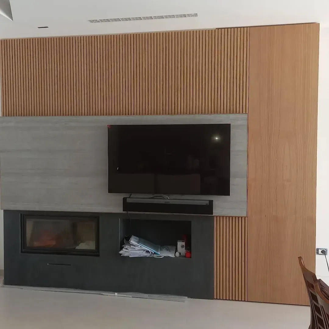 Parete rivestita in legno con camino, TV e soundbar.