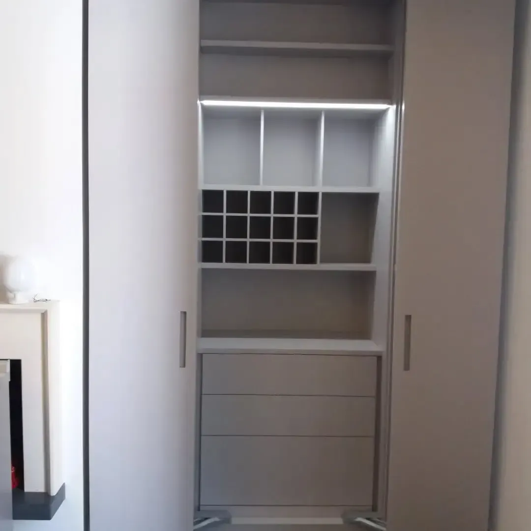 Mobiletto a muro grigio chiaro con ante aperte che rivelano ripiani, cassetti e un portabottiglie.
