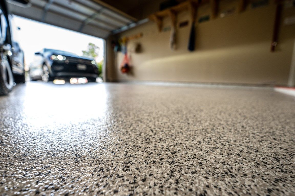 Shiny, speckled epoxy garage floor with a car in the background.