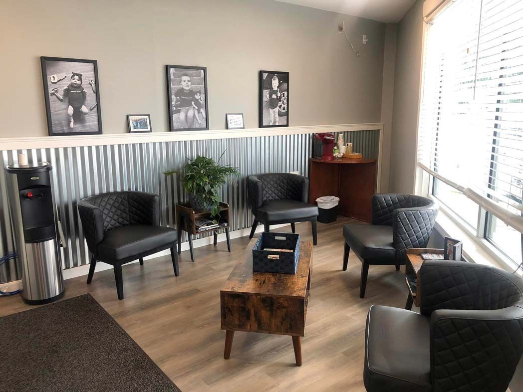 A waiting room with chairs , a coffee table and a water cooler.
