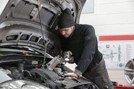 a man is working on the engine of a car in a garage .