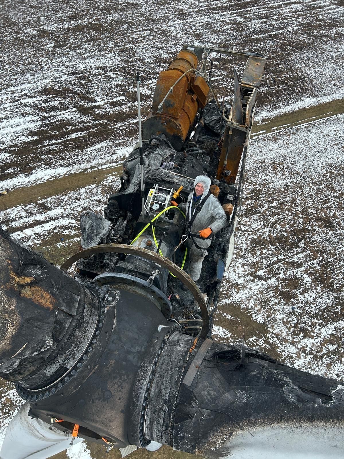 Een arbeider inspecteert een grote zwarte industriële machine op een besneeuwd veld.