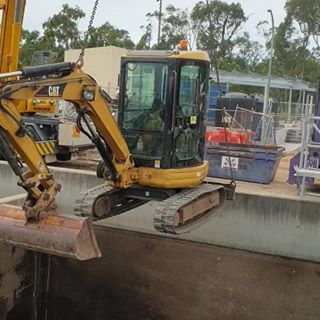 A yellow excavator is digging a hole in the ground.
