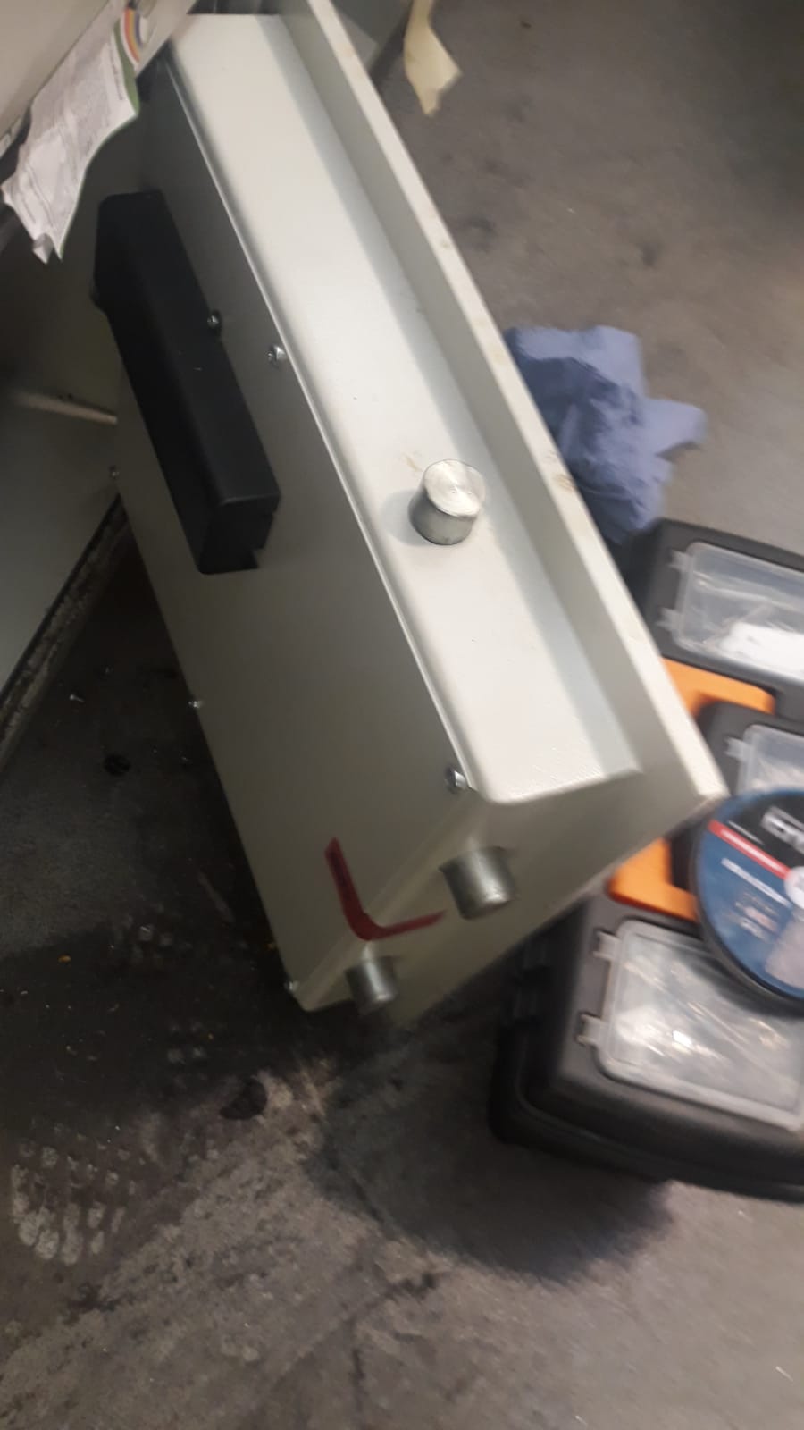 A white safe is sitting on the floor next to a toolbox.