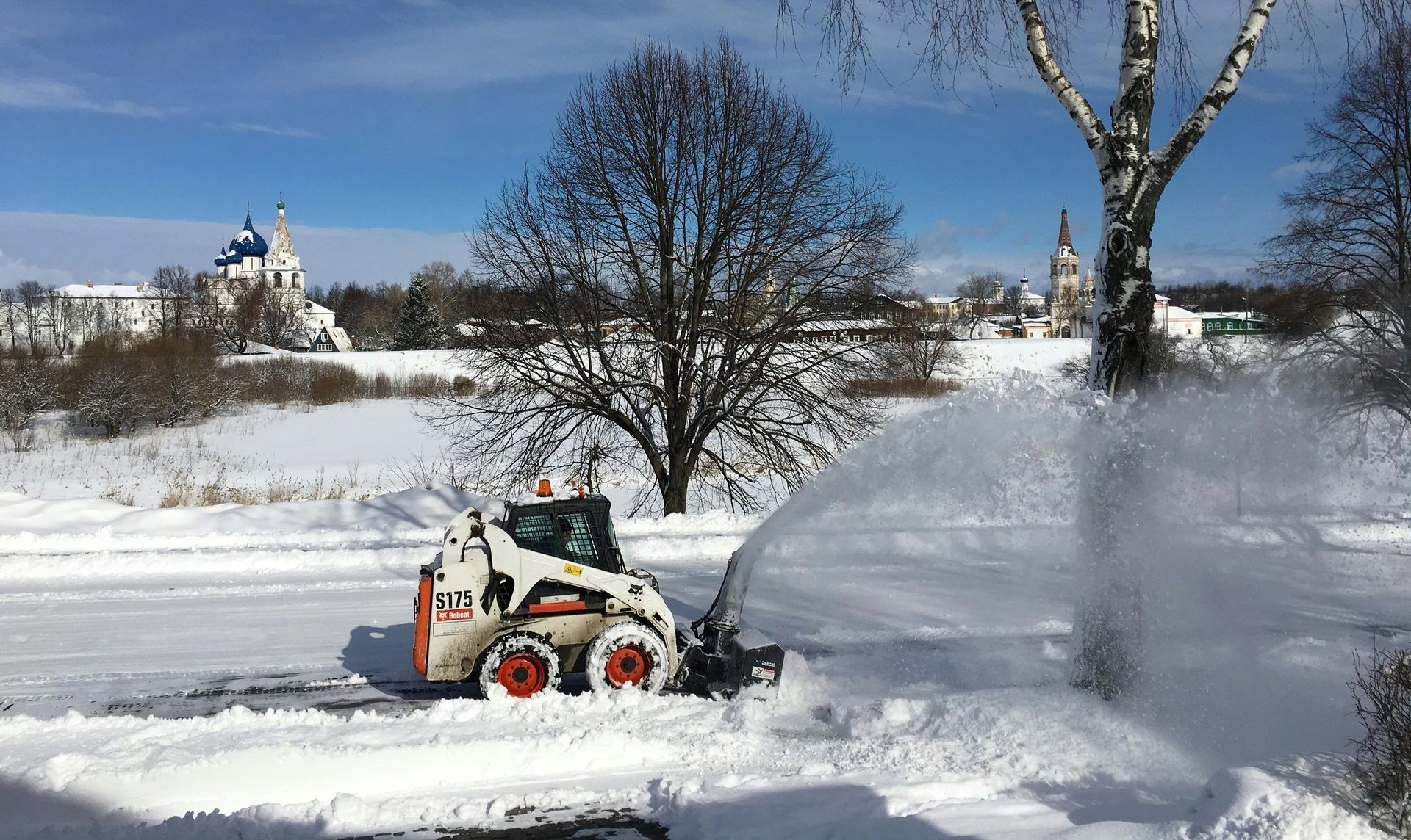 A snow blower is blowing snow in a snowy field.