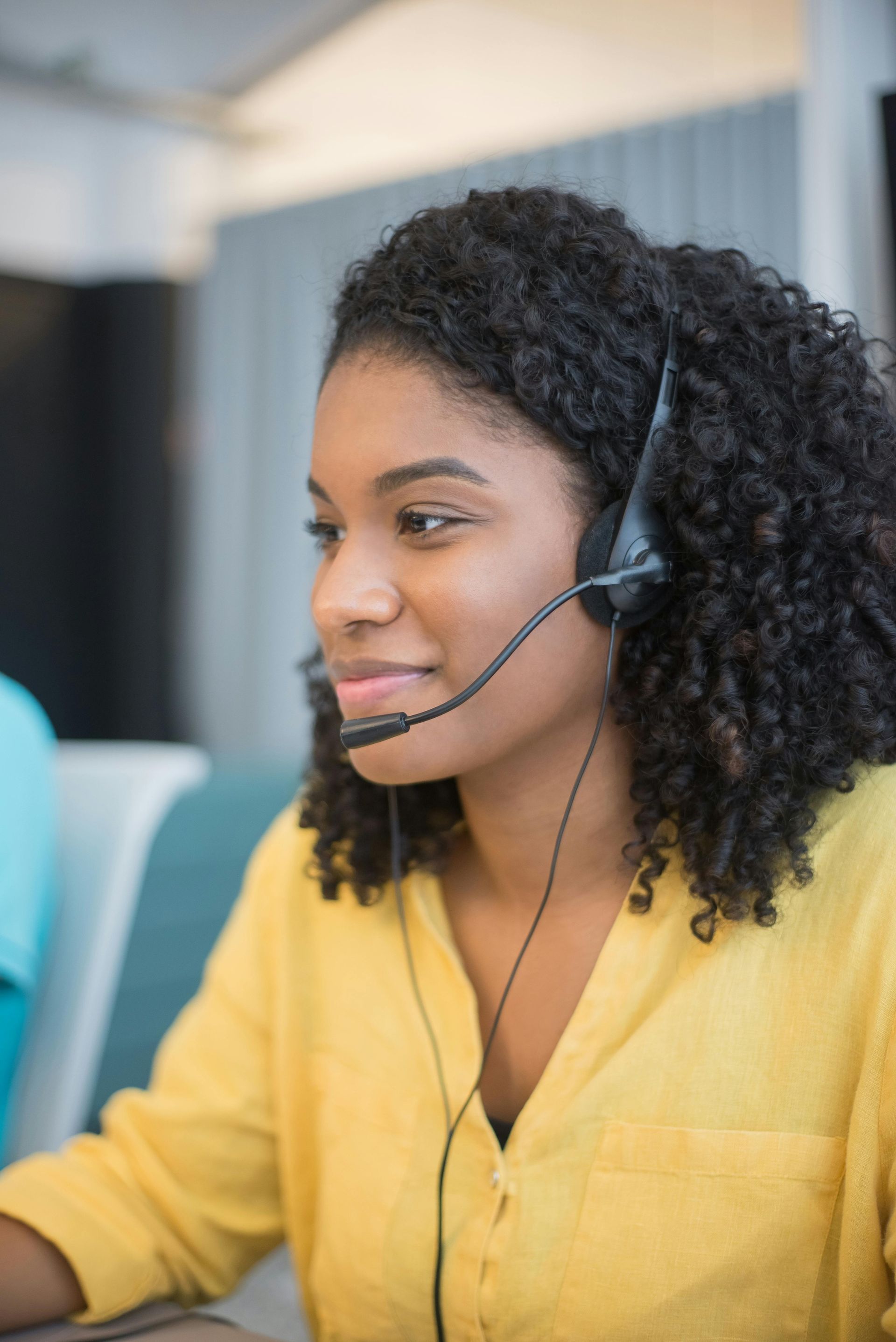 A woman wearing a headset is sitting at a desk in front of a computer.