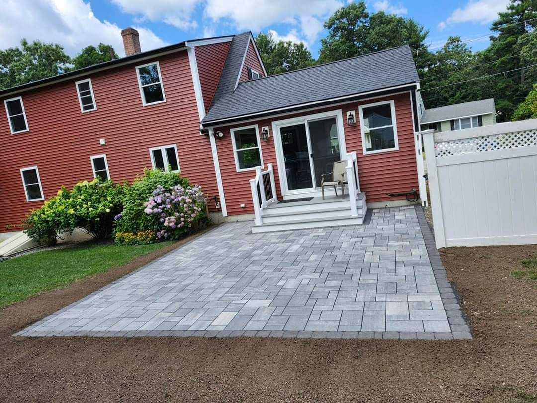 Brick patio next to a red house with a sliding glass door.