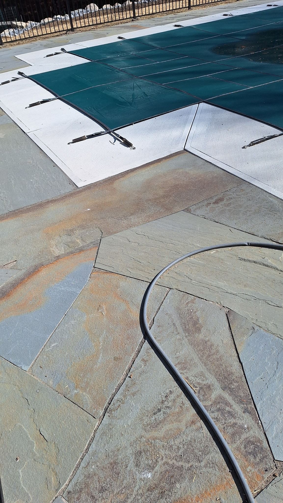 Rusted metal roof with dark blue pool cover and electrical cord.