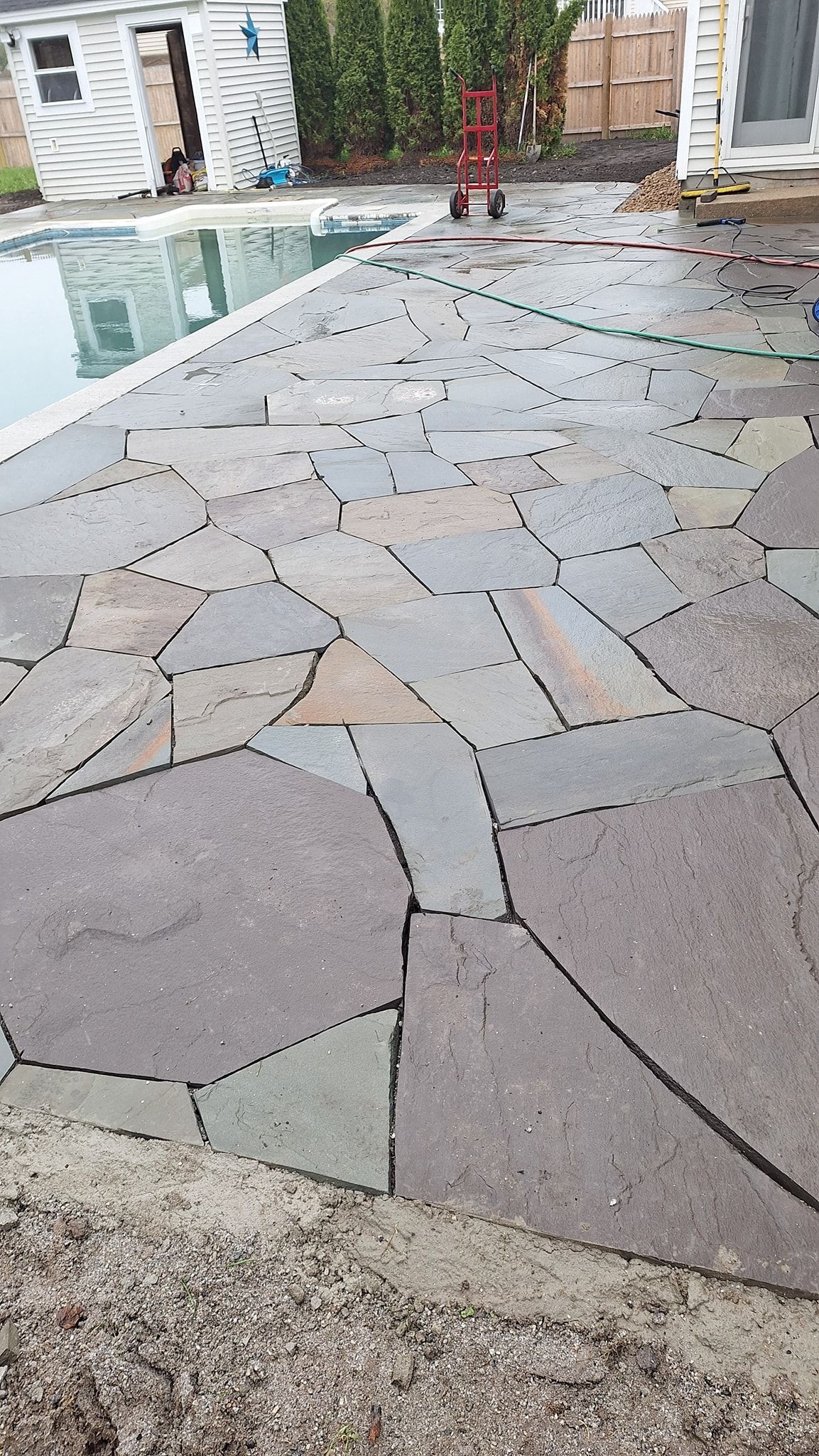 Flagstone patio surrounding a pool; gray, blue, and green stones.