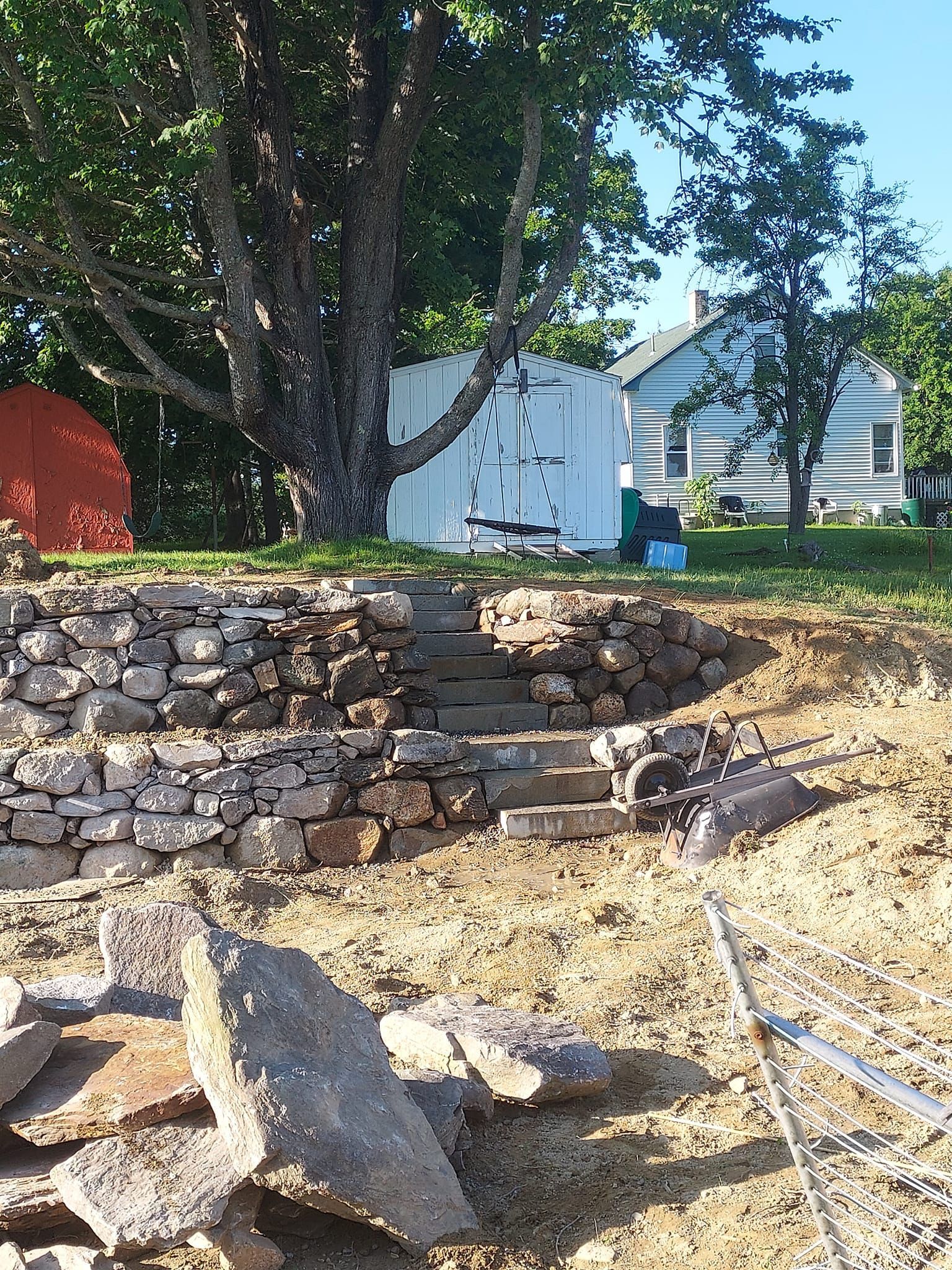 Stone steps lead up a hill with a rock wall and a shed.