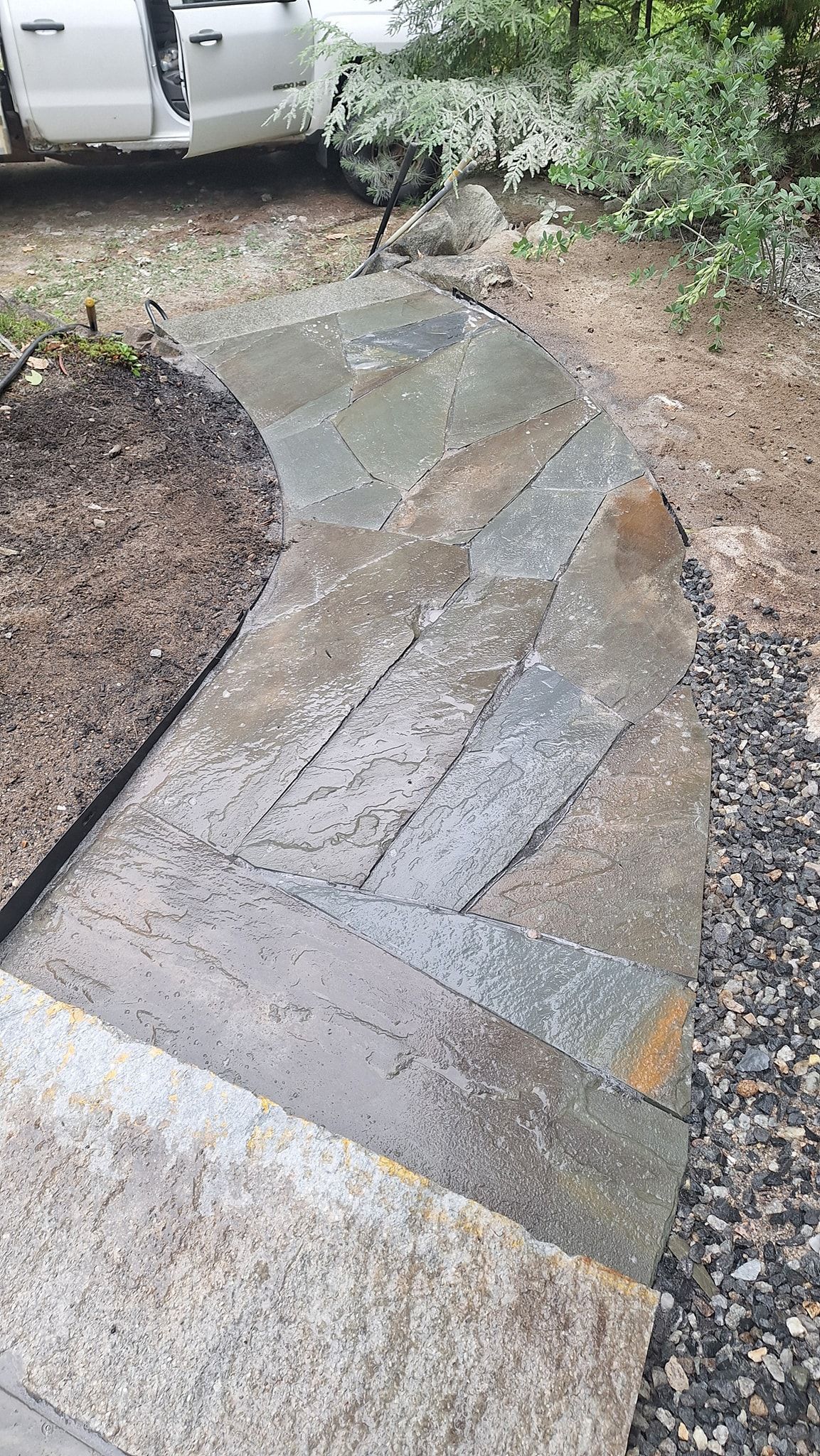 Stone steps leading up a pathway with mulch and gravel.