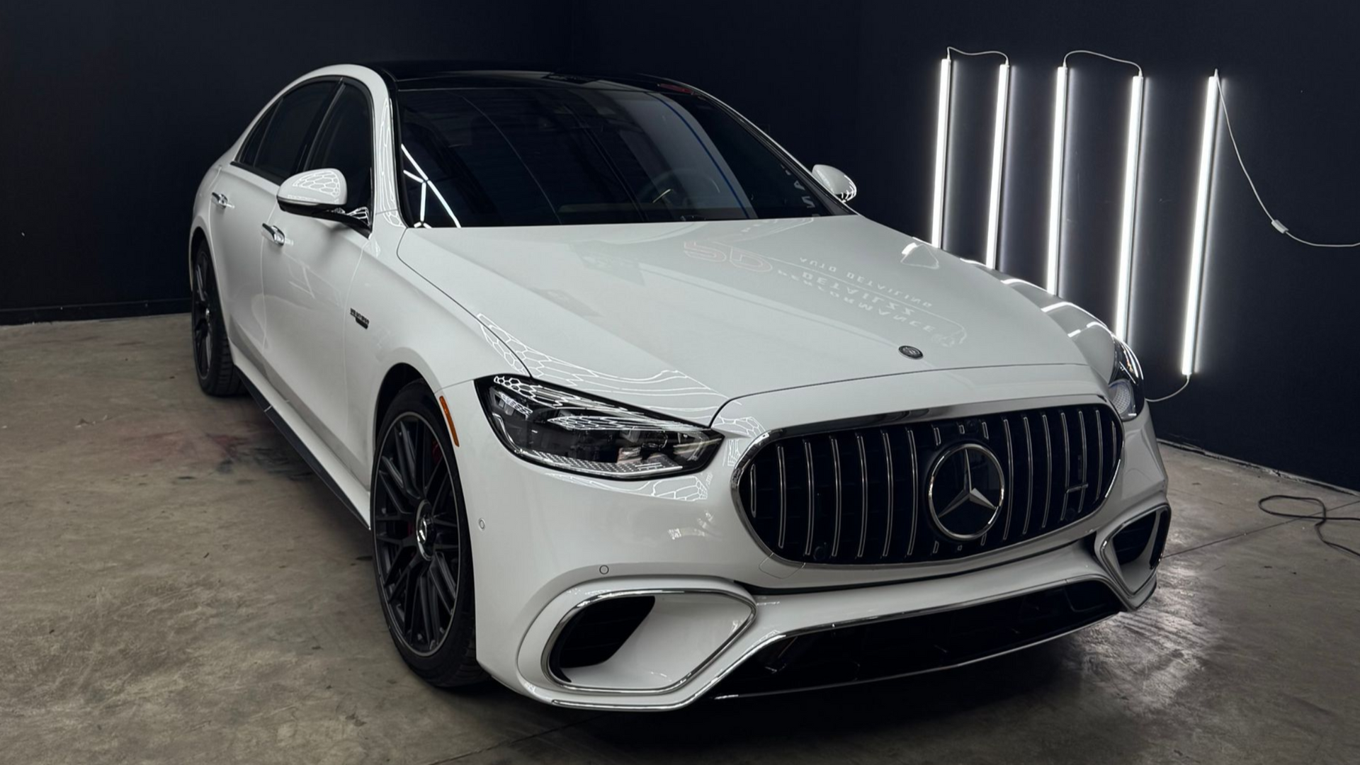 White Mercedes-Benz sedan in a detail shop with black accents.