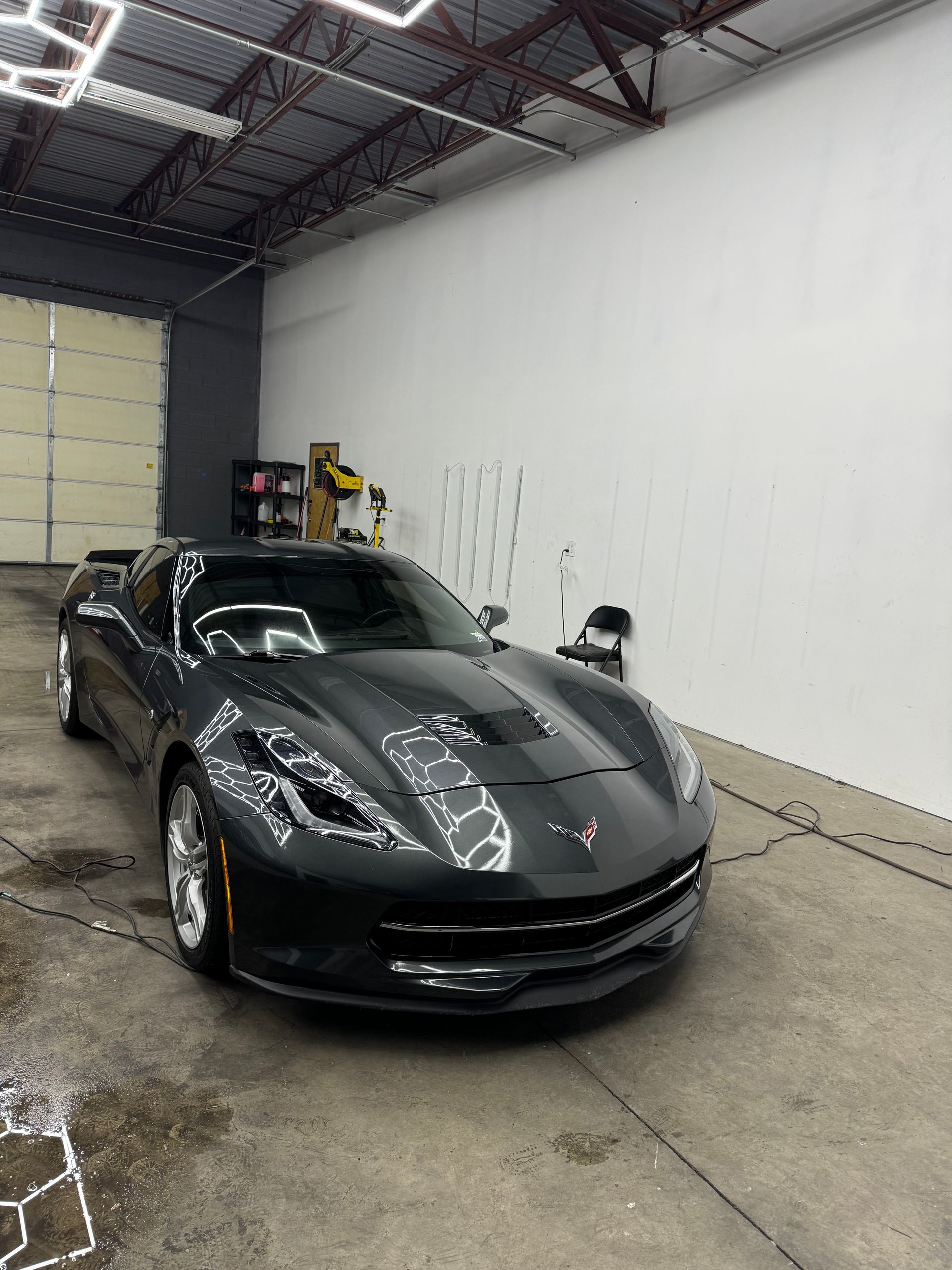 Dark gray Corvette in a car detailing bay.