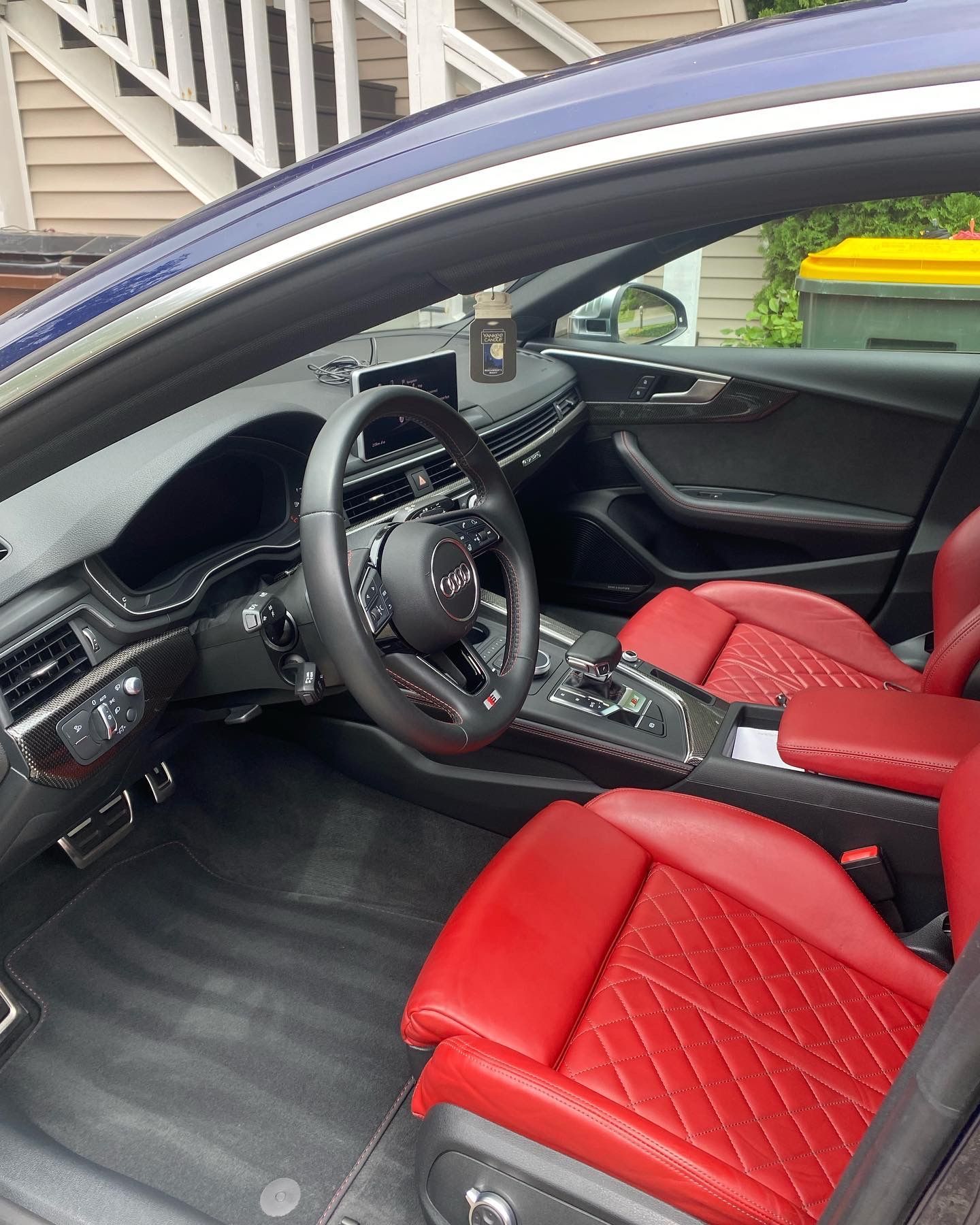 Interior of a blue Audi with red leather seats, black dashboard, and steering wheel.