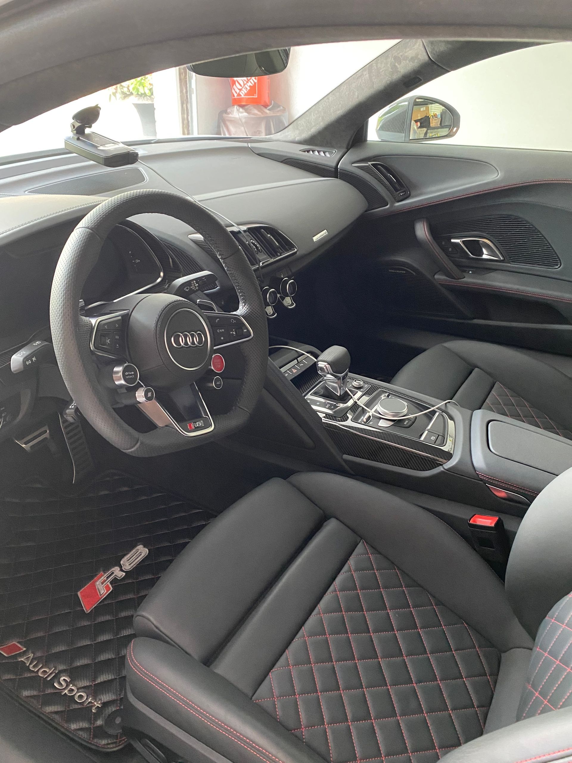Black Audi R8 interior with quilted seats, black and chrome accents, and a steering wheel with the Audi logo.