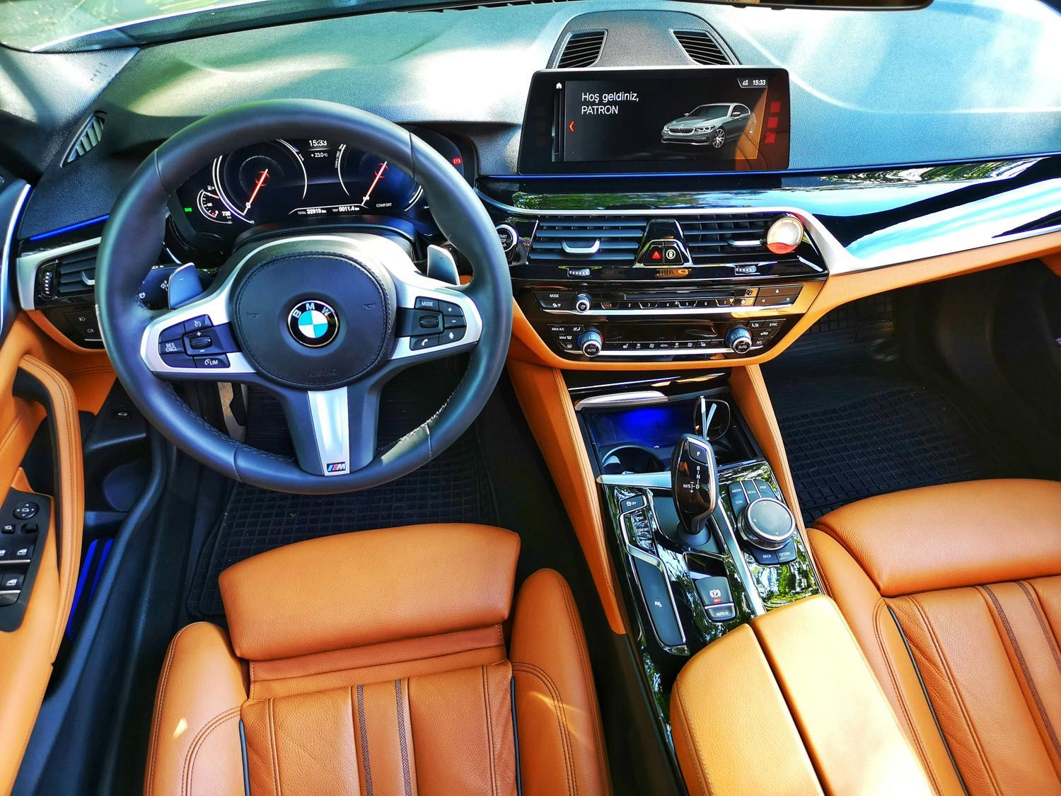 Interior of a BMW car with brown leather seats, a black dashboard, and a silver steering wheel.