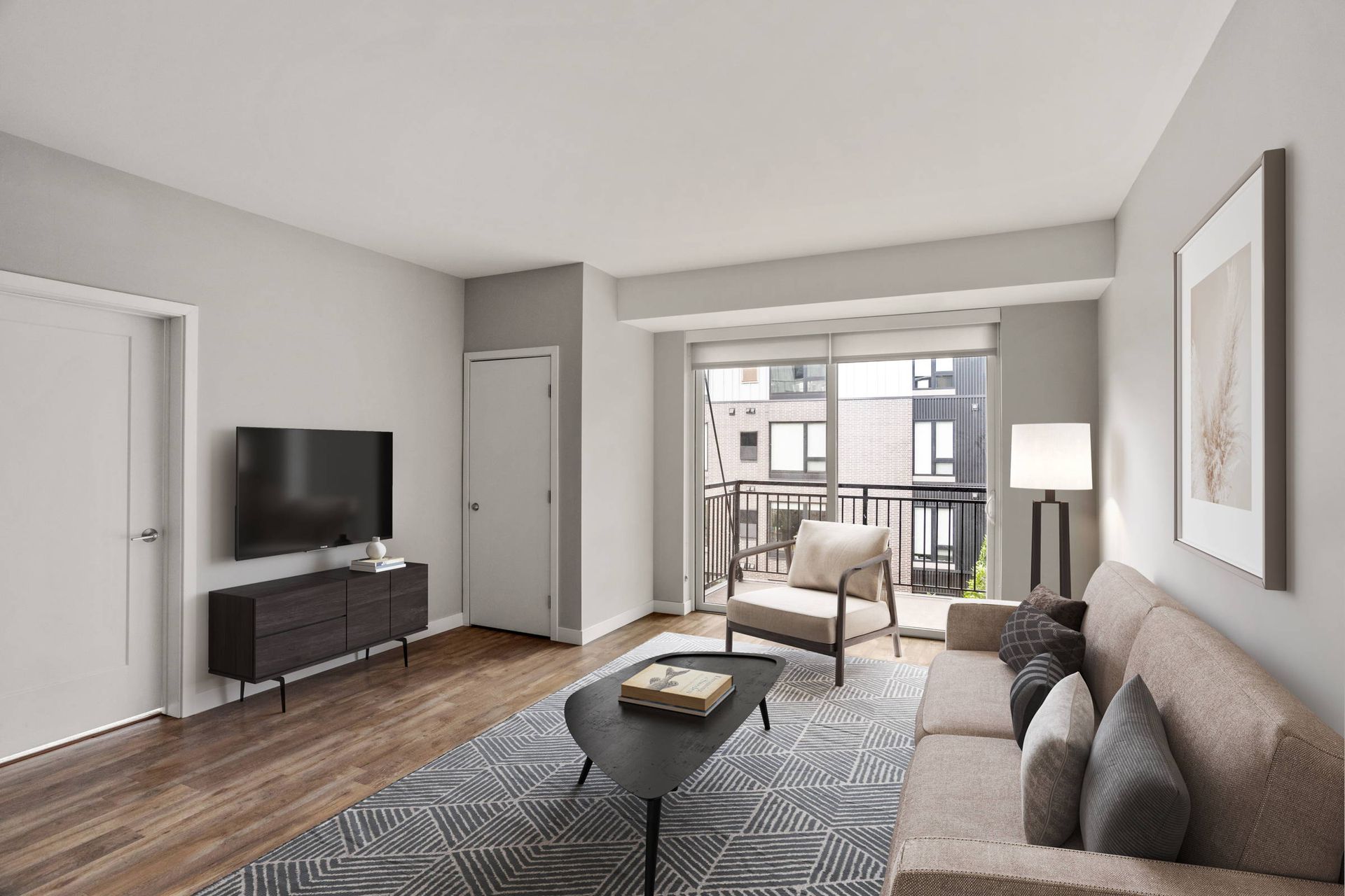 Modern living room with a beige sofa, patterned rug, coffee table, television on a stand, and balcony view.
