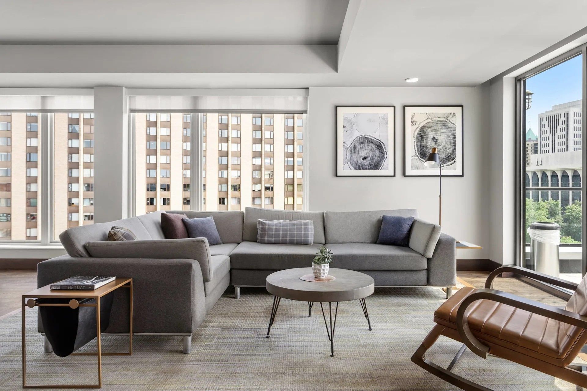A modern living room with a large gray sectional sofa, a round coffee table, and a brown leather rocking chair.