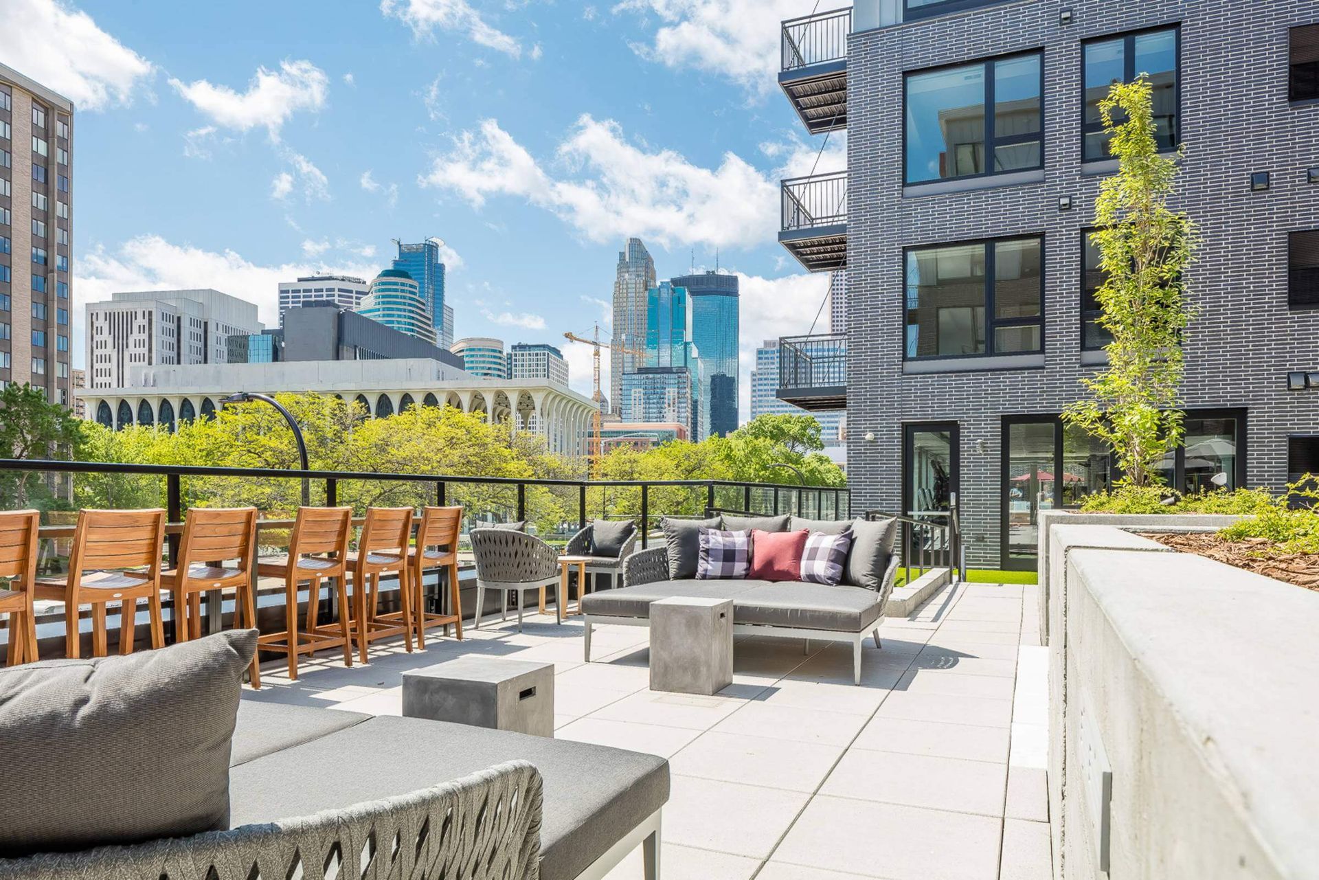 A patio with a couch , chairs , tables and a view of the city.