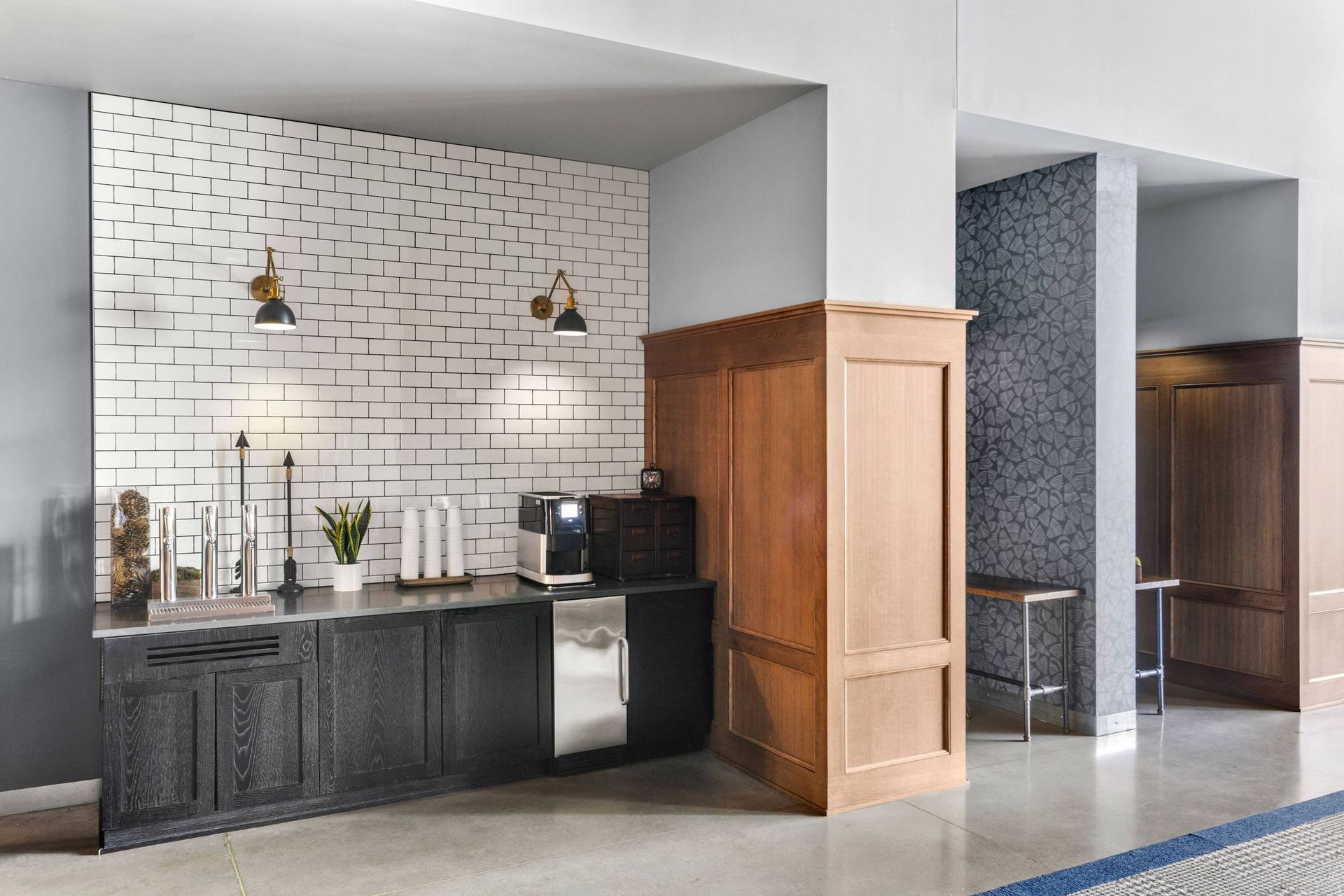 A kitchen with a brick wall and stainless steel appliances in a hotel lobby.