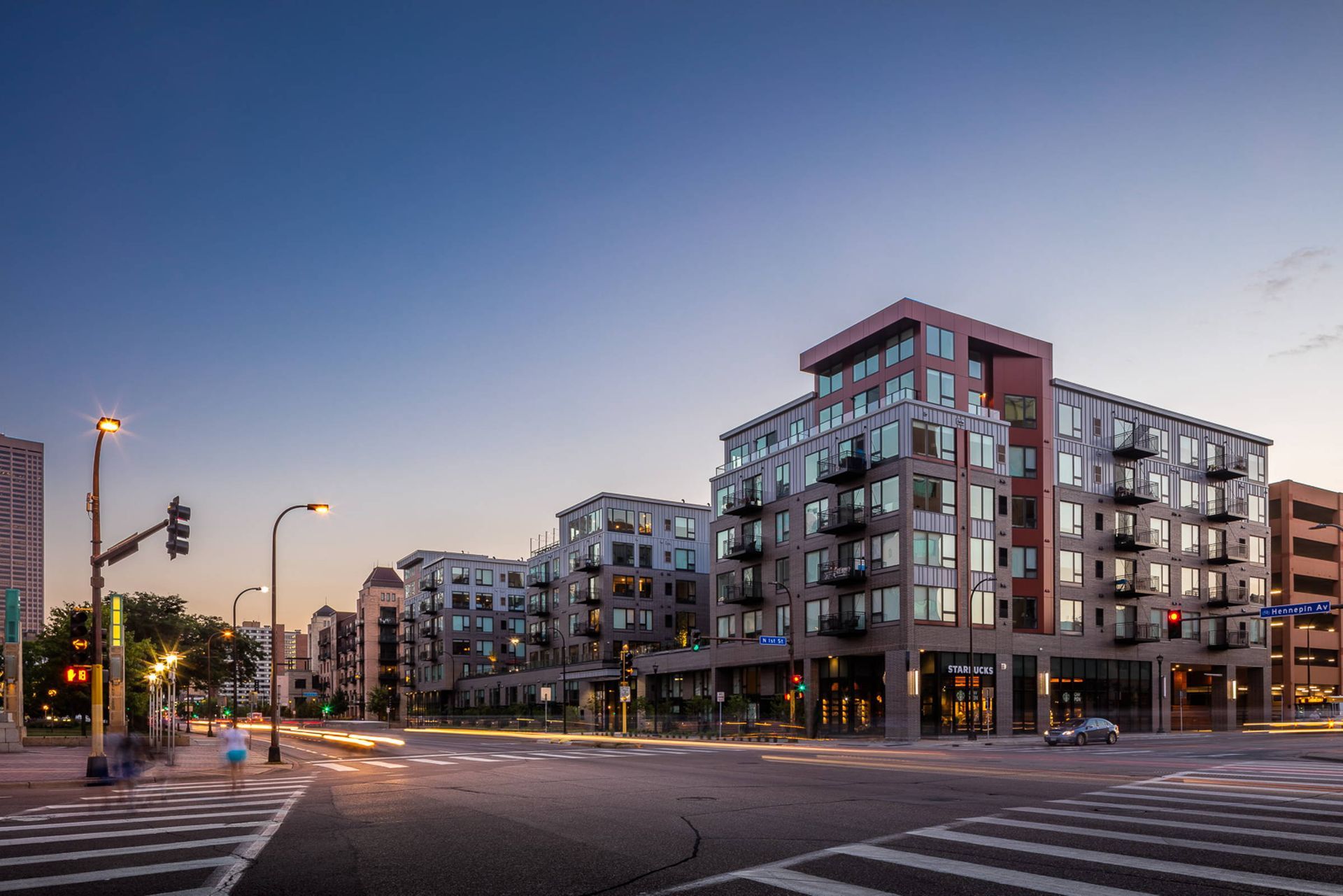 A large apartment building is sitting on the corner of a city street.