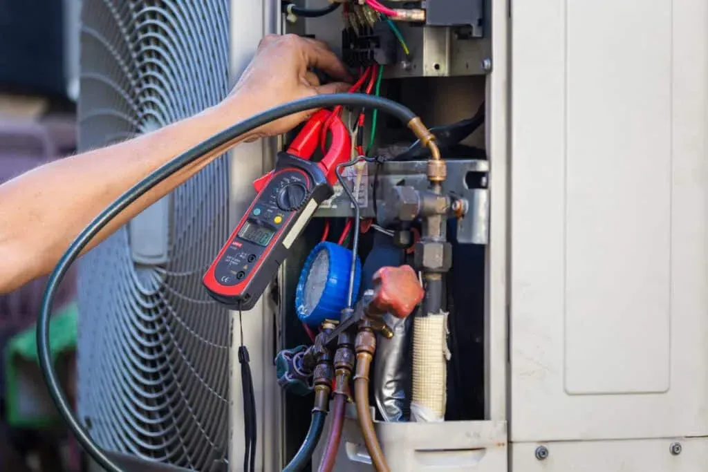 A man is working on an air conditioner with a clamp.