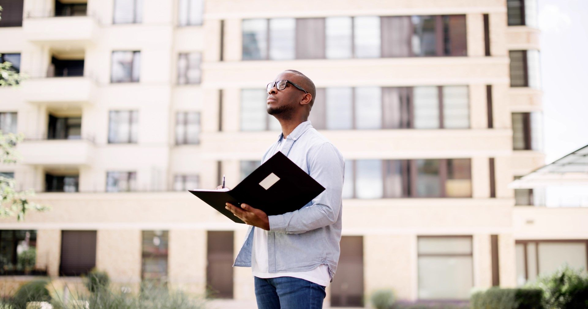Realtor with a folder, standing in front of a building