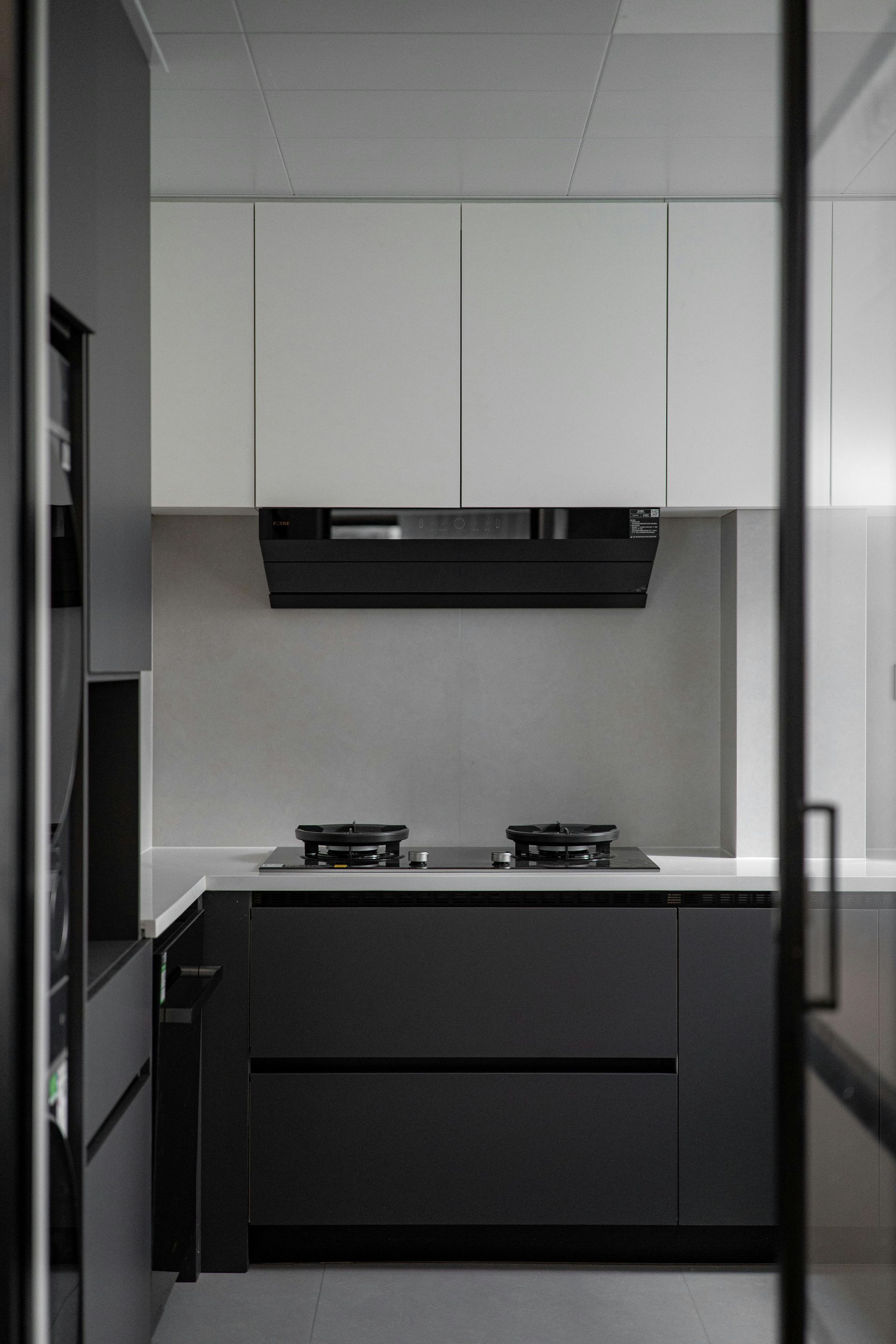 Modern kitchen with dark lower cabinets, light upper cabinets, and a black range hood.
