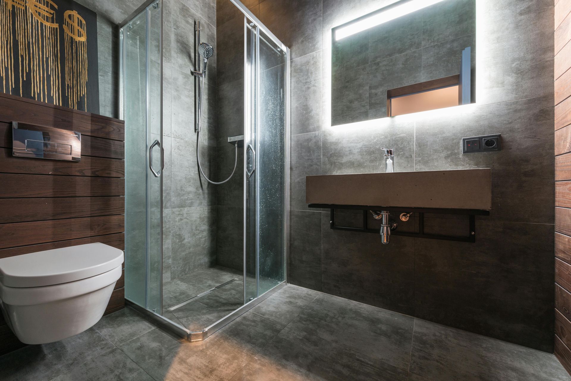 Modern bathroom with gray tiled walls, shower, floating sink, and toilet.