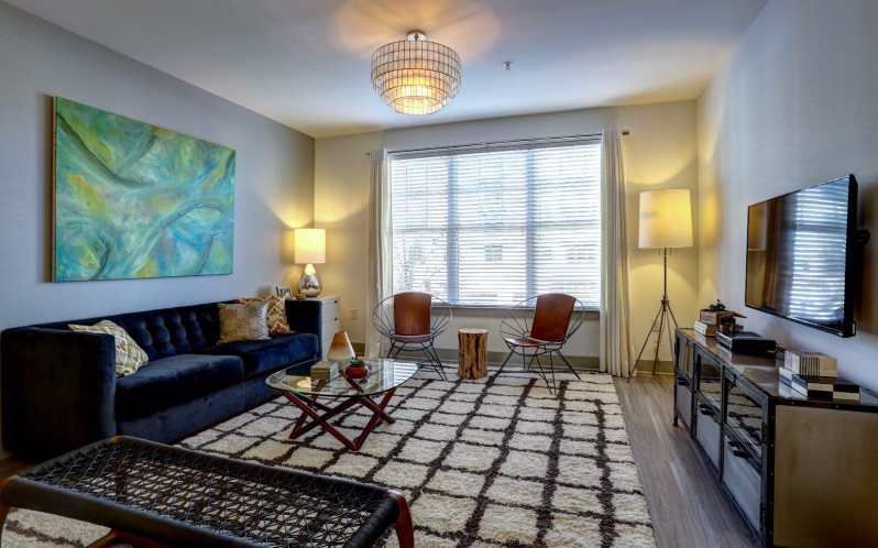 Living room with a blue sofa, modern art, patterned rug, and TV.