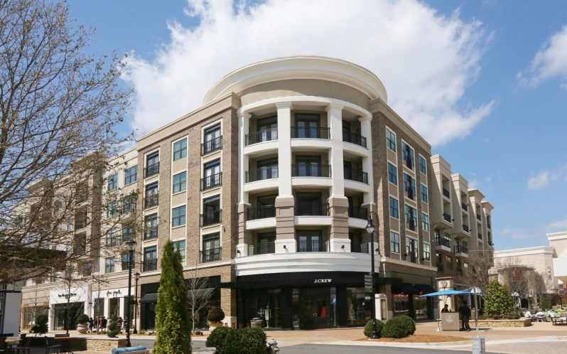 Building with storefronts, balconies, and a round top under a partly cloudy sky.