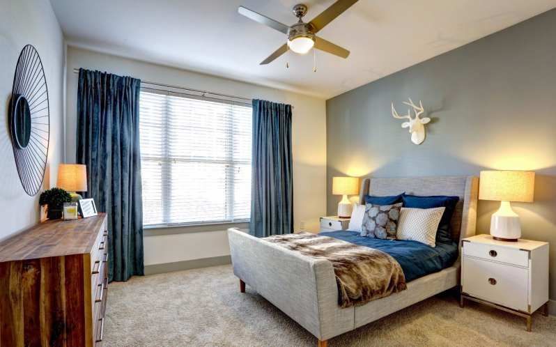 Bedroom with a bed, dresser, window, and deer head; blue and beige color scheme.