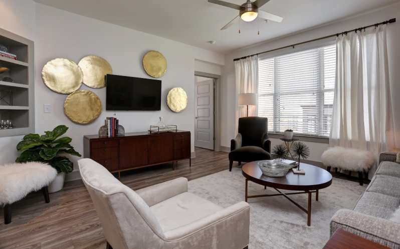 Modern living room with gold accents, a dark wood cabinet, and a gray sofa.