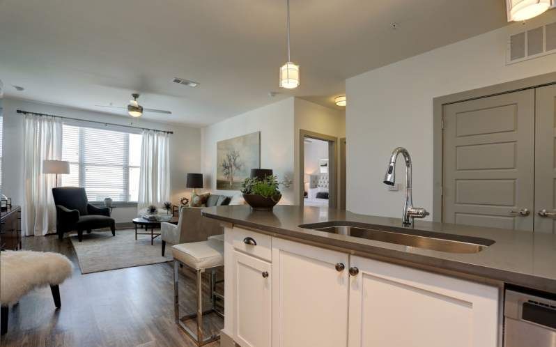 Open concept apartment with kitchen island, living area, and natural light.