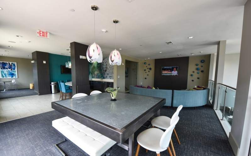 Modern lounge area with gray table, white chairs, and blue sofa.