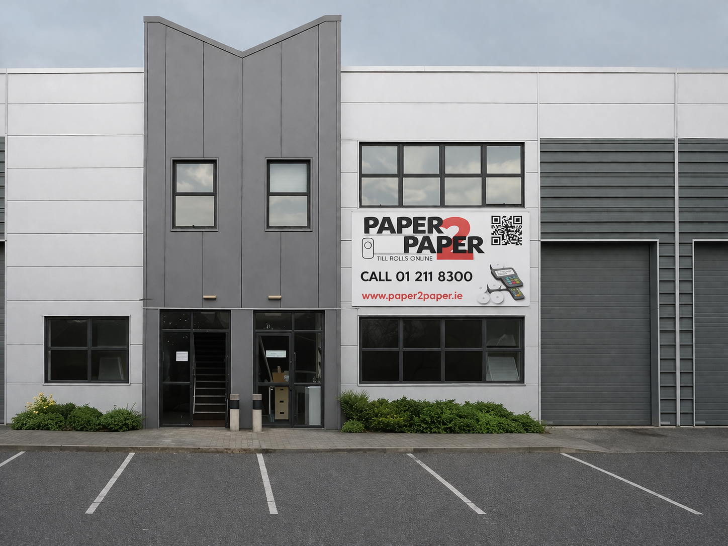 Modern industrial building facade with a large Paper Paper sign and parking spaces in front