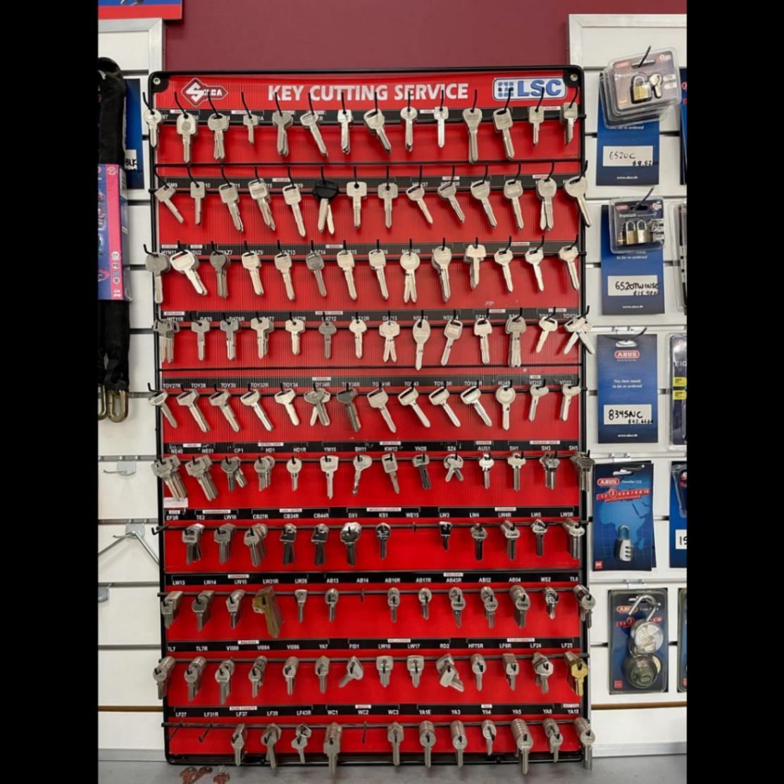 A Bunch of Keys Are Hanging on A Rack that Says Key Cutting Service — Lock & Door in Wodonga, VIC
