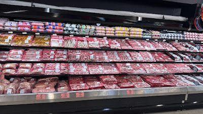 A refrigerator filled with lots of meat in a grocery store.