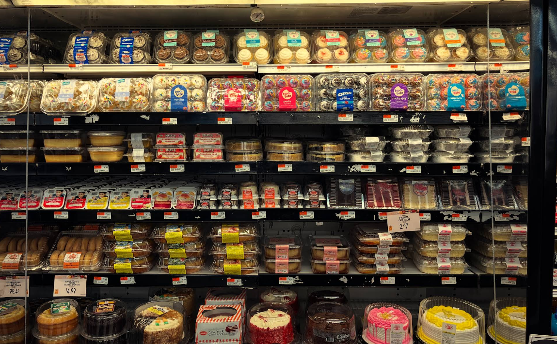 A grocery store aisle filled with lots of cakes and pastries.